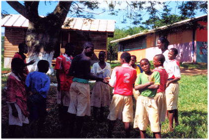 Tylar Bertie, group member, and several boys from the St. John Bosco Home for Boys, under a tree